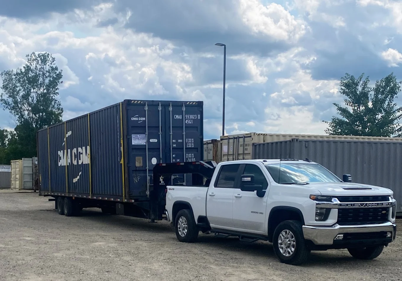 Rollback truck hauling container — statewide delivery. Call (517) 331-9399.